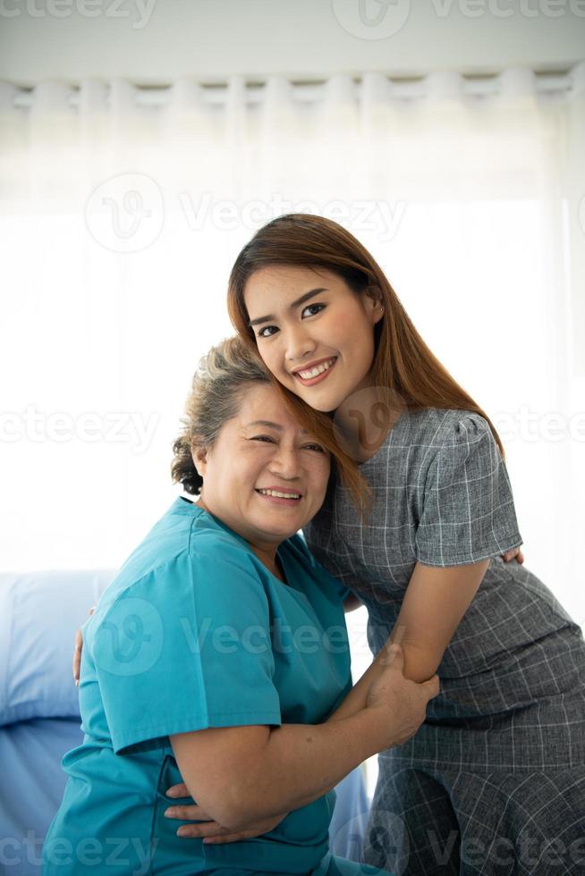 Tochter einer älteren Patientin, die die Mutter versorgt und ermutigt foto