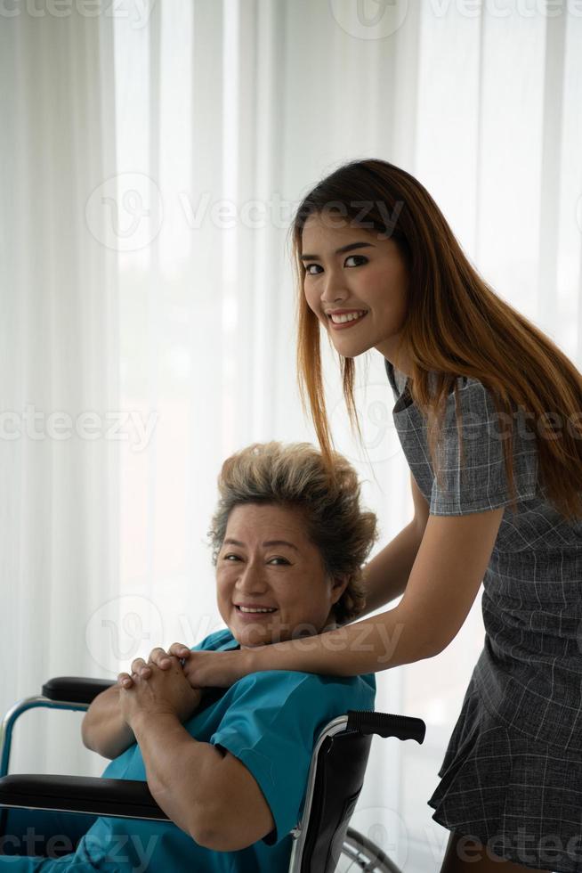 Tochter einer älteren Patientin, die die Mutter versorgt und ermutigt foto