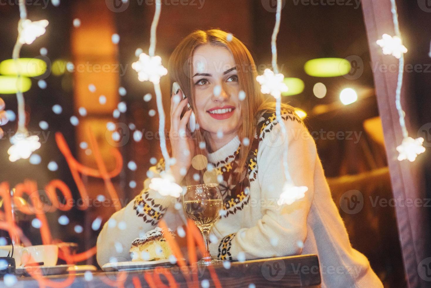 junge schöne frau, die im café sitzt und wein trinkt. weihnachten, neujahr, valentinstag, winterferienkonzept foto