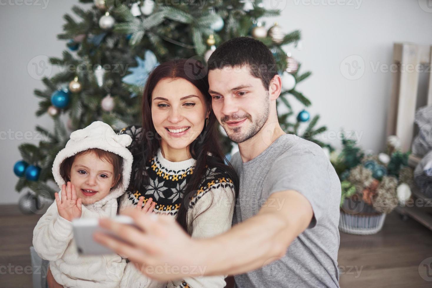 Familie versammelte sich mit einem Tablet um einen Weihnachtsbaum foto