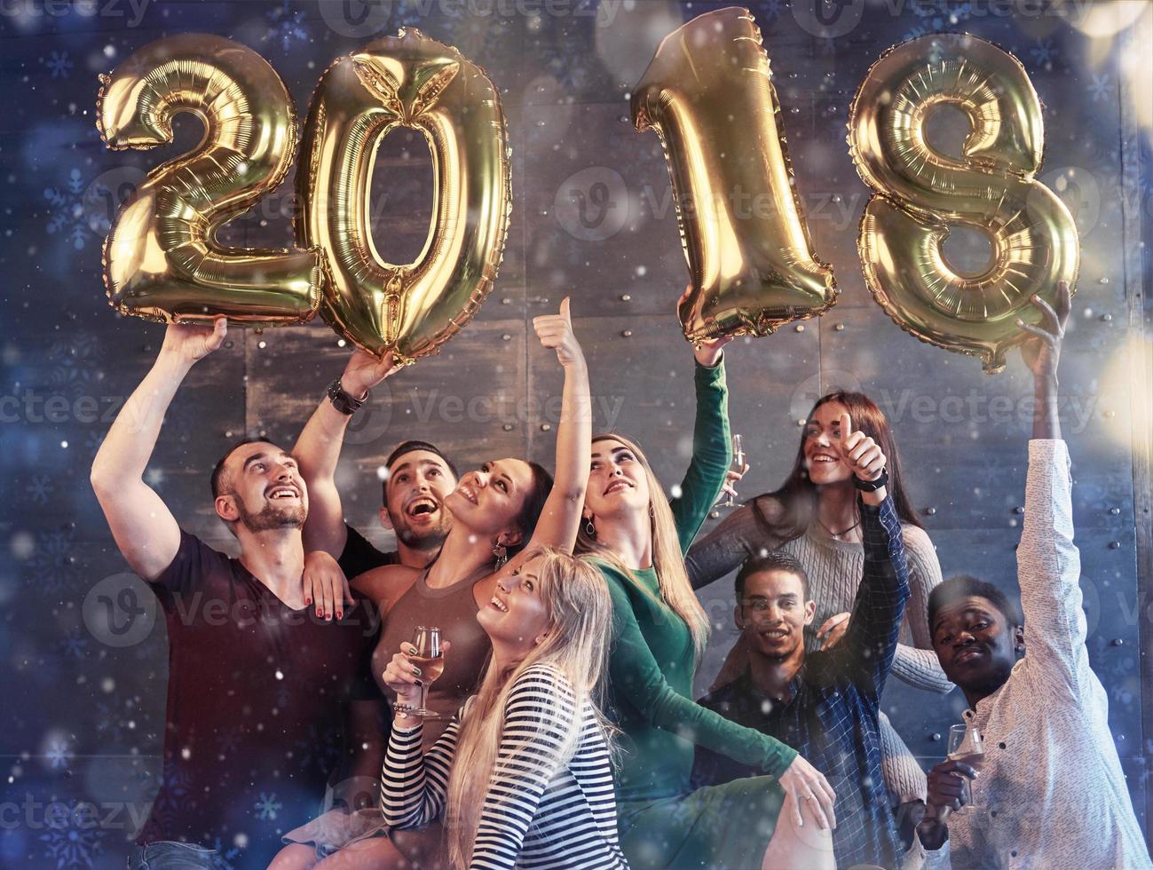 Eine Gruppe fröhlicher junger Leute hält Zahlen, die die Ankunft eines neuen Jahres 2018 anzeigen. Die Party ist der Feier des neuen Jahres gewidmet. konzepte über den lebensstil der zusammengehörigkeit der jugend foto