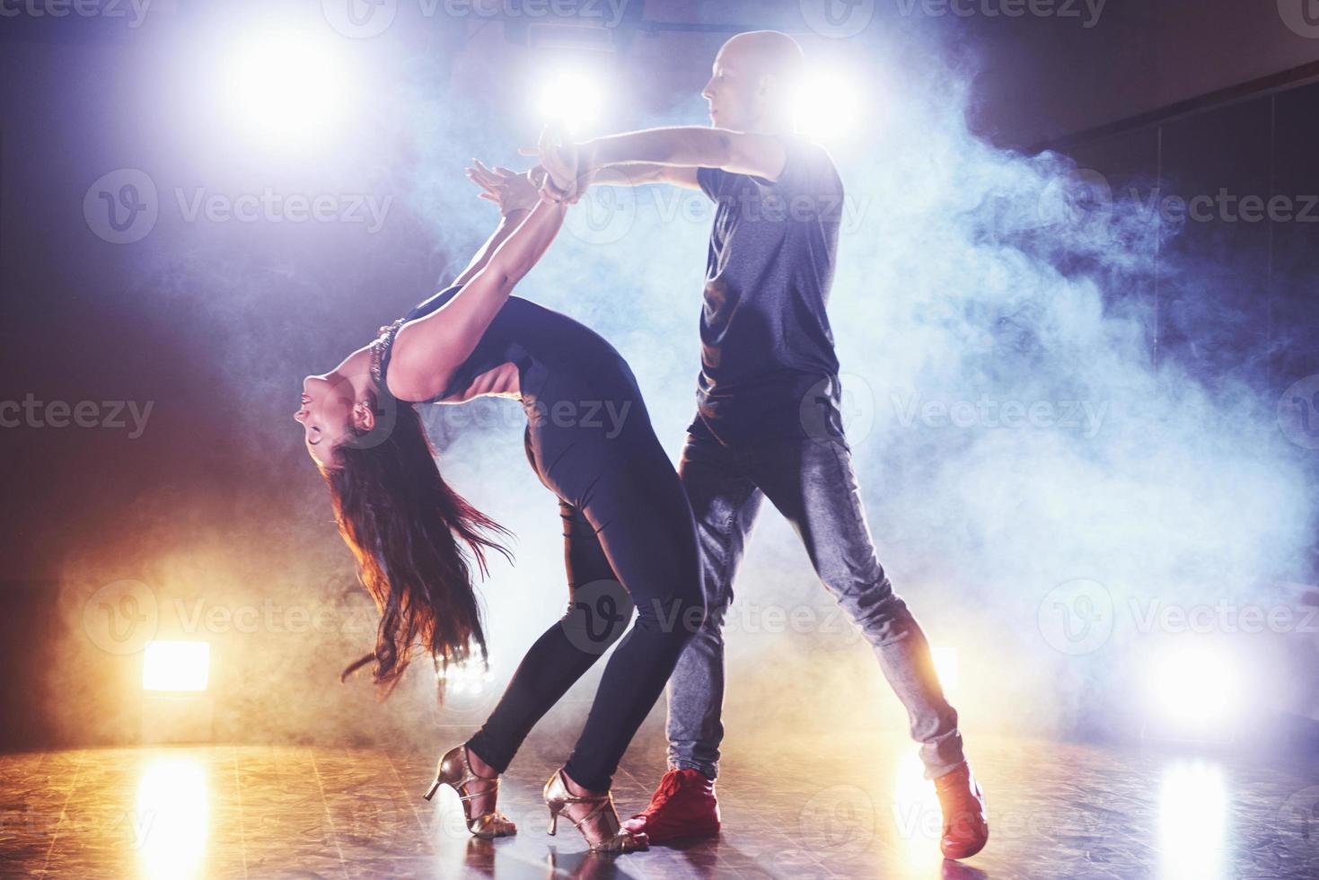 Geschickte Tänzer, die im dunklen Raum unter Konzertlicht und Rauch auftreten. sinnliches Paar, das einen künstlerischen und emotionalen zeitgenössischen Tanz aufführt foto