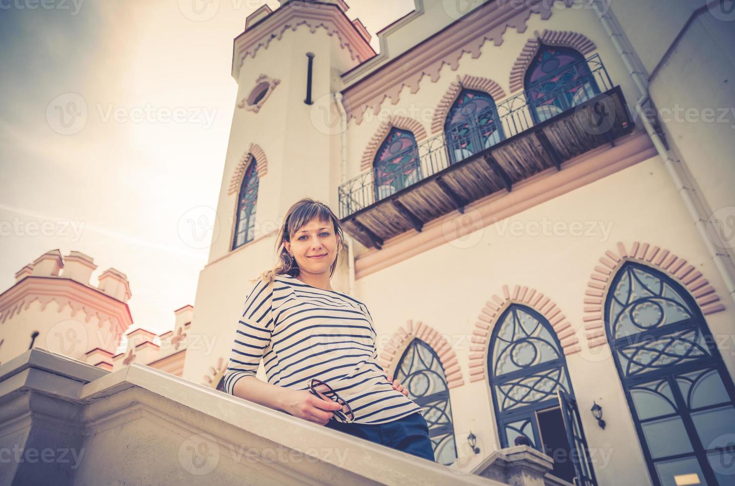 junge schöne reisende, die an sonnigen sommertagen in der nähe des palastschlossgebäudes in kosava kossovo posiert foto