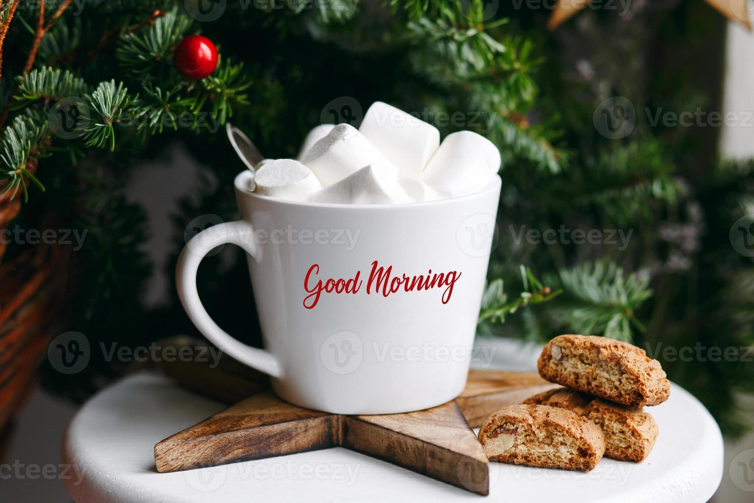 Kaffee in einer weißen Tasse mit Marshmallows. morgendlicher festlicher kaffee mit traditionellen italienischen cantuccini-mandelkeksen. eine tasse kaffee auf einem hintergrund grüner tannenzweige auf einem weißen stand. foto