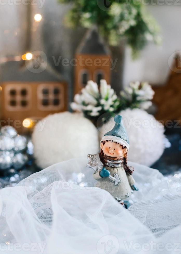 Porzellanfiguren von Kindern in einem Weihnachtsdekor. Winterfiguren eines Jungen und eines Mädchens mit Geschenken auf dem Hintergrund von Häusern und Kegeln. Weihnachtsgrußkarte. Platz kopieren. foto