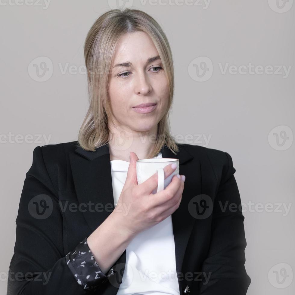 frau, die formelle geschäftskleidung trägt, die tasse kaffee hält und denkt. geschäftsfrau arbeitgeber mit pause, harter tag abgeschlossen. foto