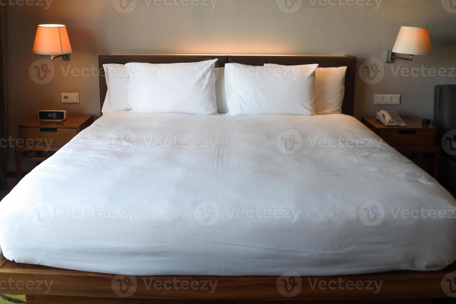 komfortables Schlafzimmer mit ordentlichem weißen Bett und Leselampe auf beiden Seiten foto