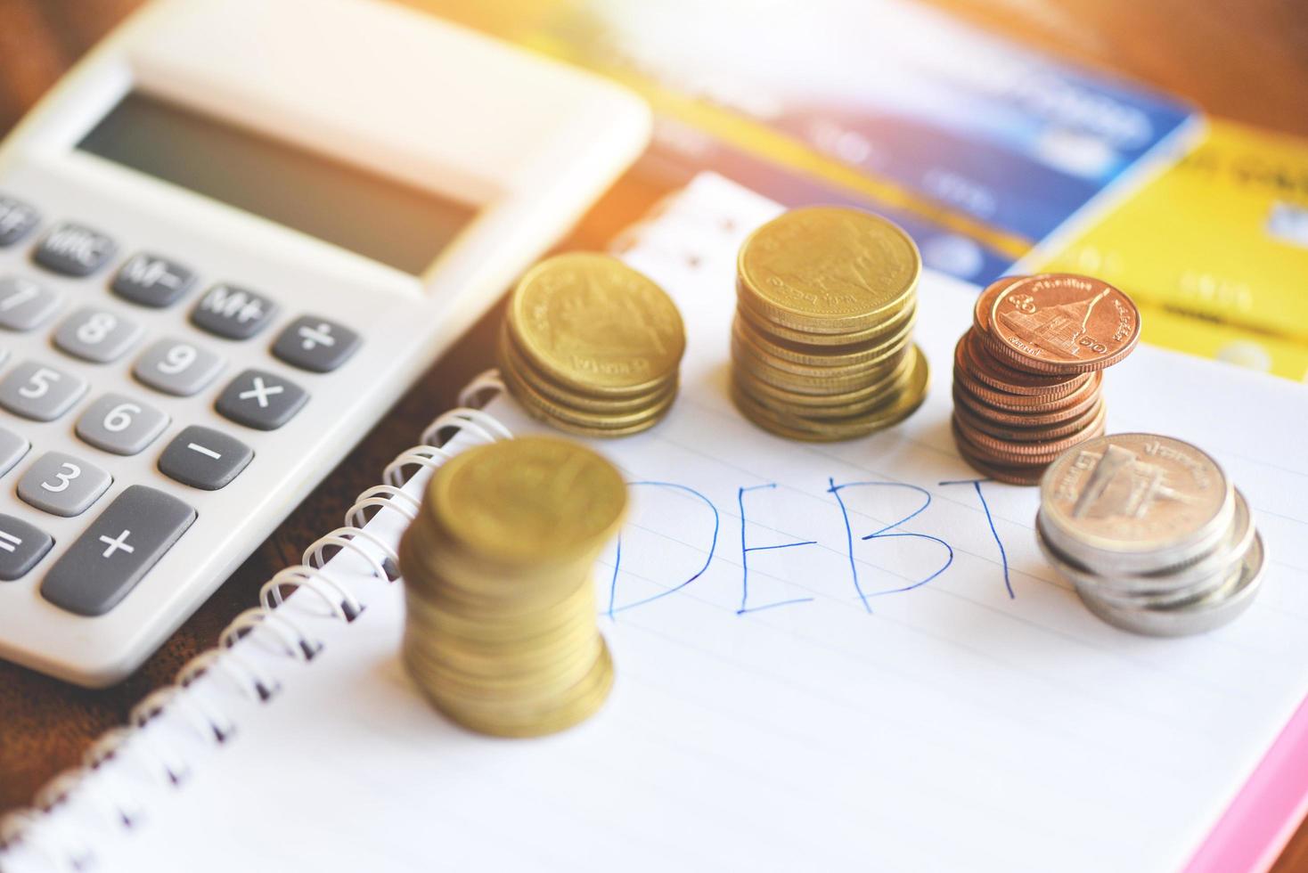 Taschenrechner und Münzstapel auf Notizbuchpapier mit Schuldenkreditkarte im Büro Finanzzählung Schuldenmanagementkonzept foto