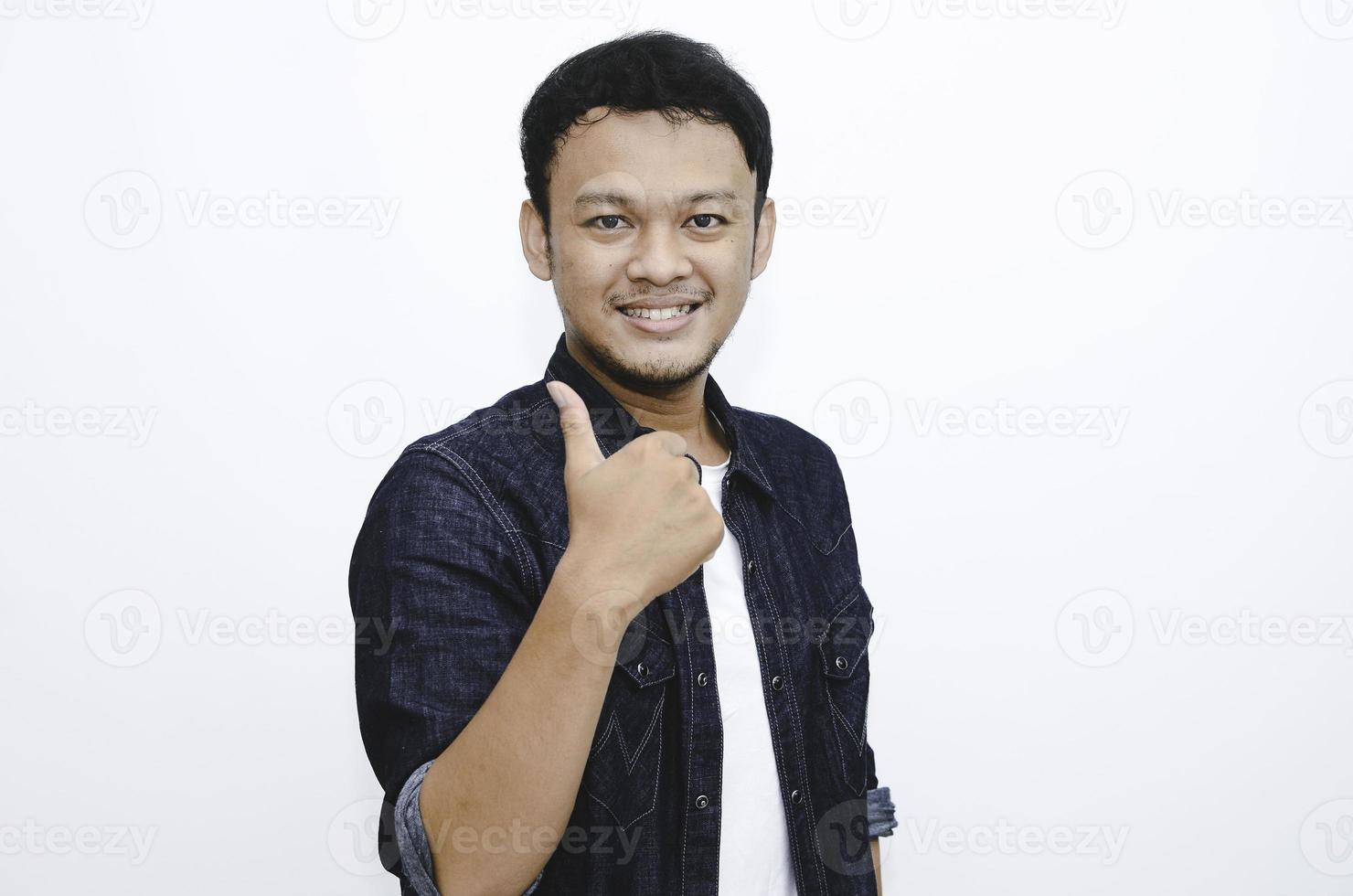 junger asiatischer mann trägt weißes hemd mit glücklich lächelndem gesicht und daumen hoch foto