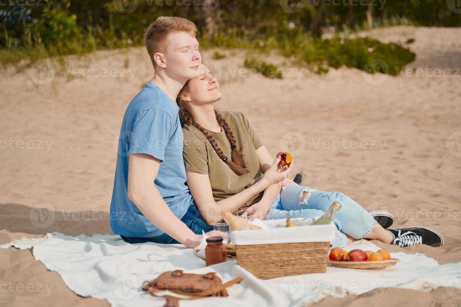 Picknick am Strand mit Speisen und Getränken. Junge und Mädchen beim Sonnenbaden foto