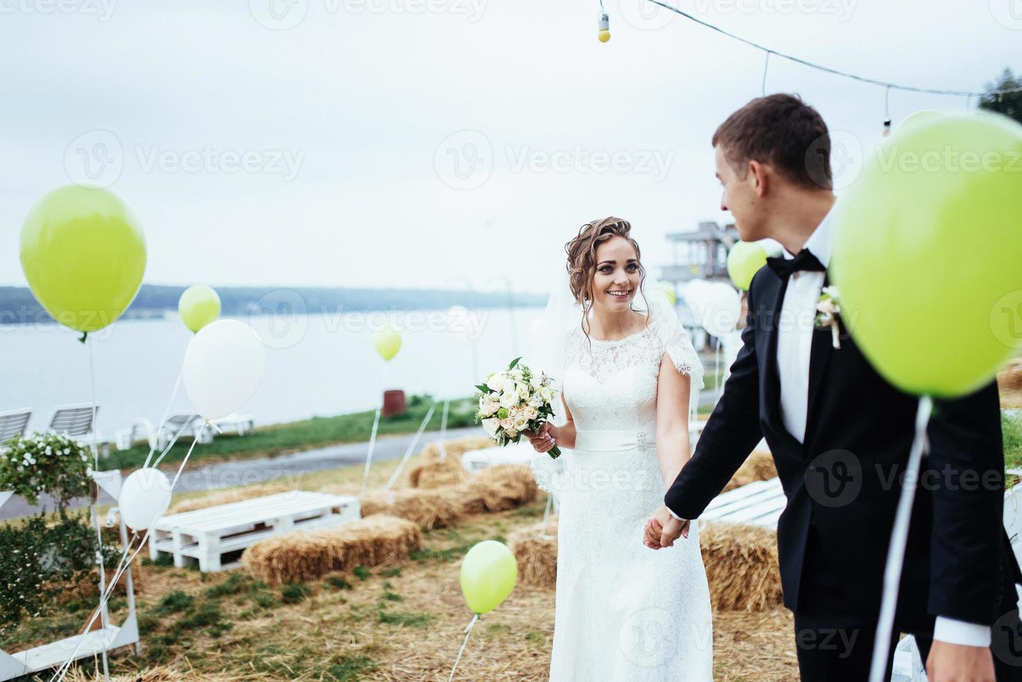 schönes junges Hochzeitspaar, das sich küsst, blonde Braut mit Blume foto