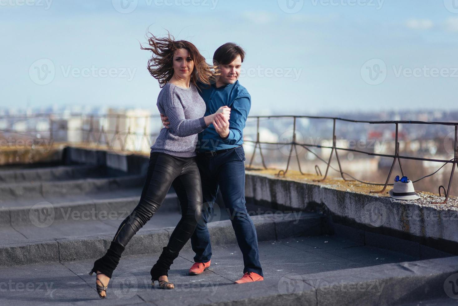 junges Paar tanzt auf dem Dach eines hohen Gebäudes foto