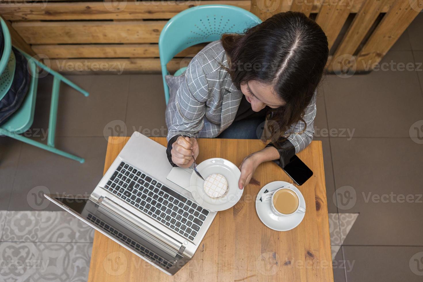 Frau isst Dessert und trinkt Kaffee während der Online-Arbeit foto