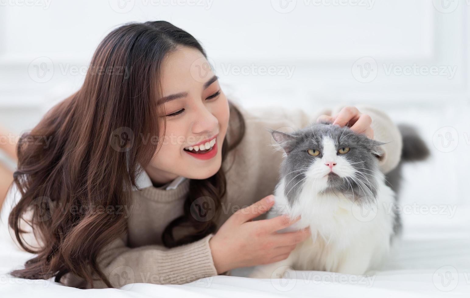 junge asiatische frau, die zu hause mit katze spielt foto