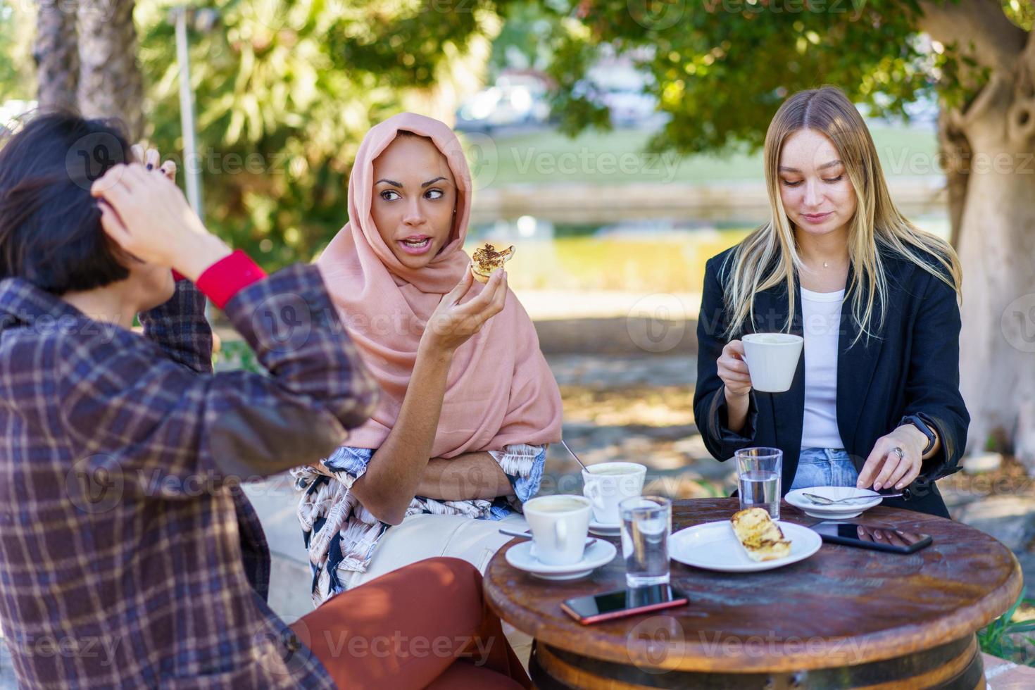 gemischtrassige frauen, die kaffeepause auf der terrasse des cafés haben foto