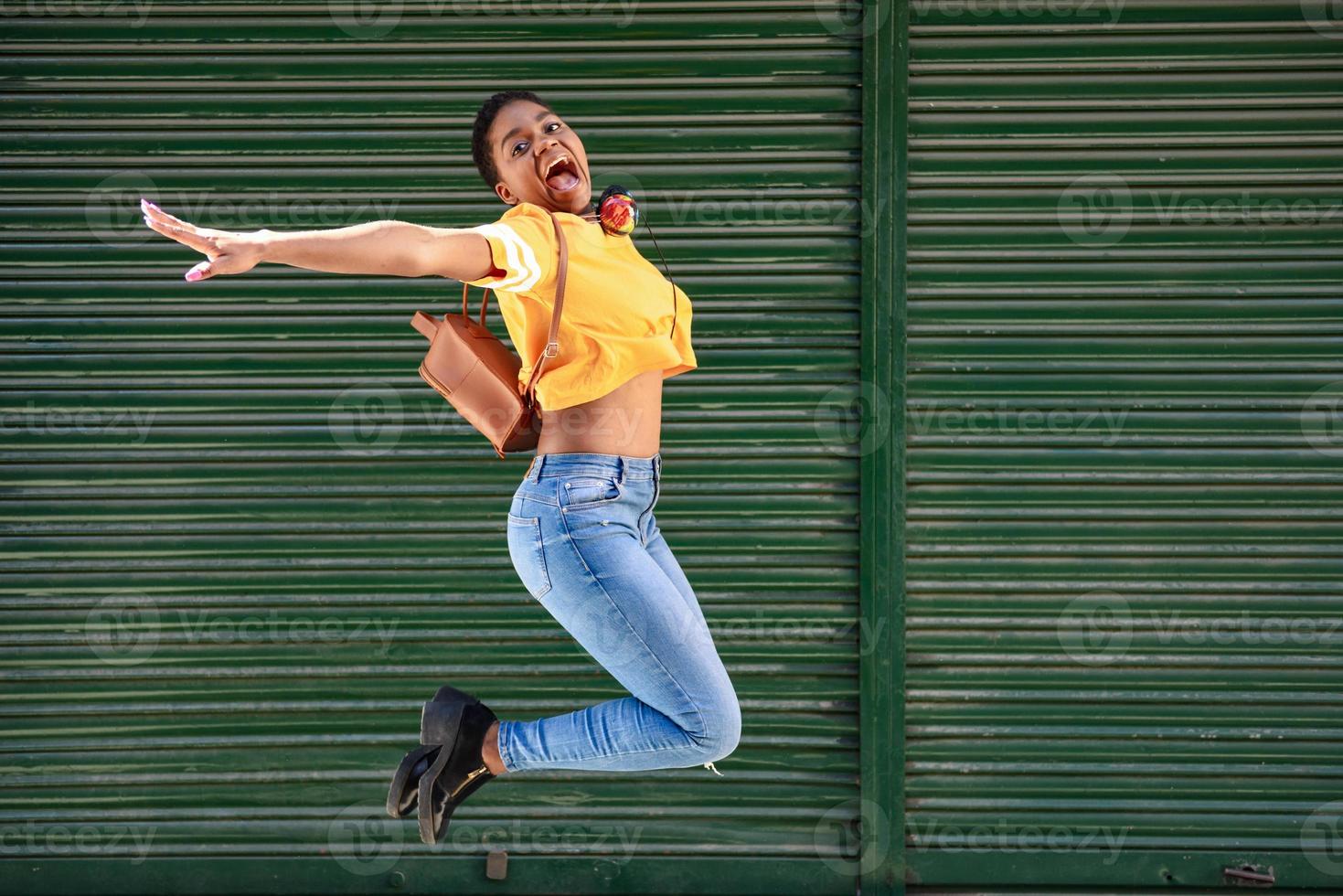 junge schwarze Frau, die auf Jalousienhintergrund springt. foto