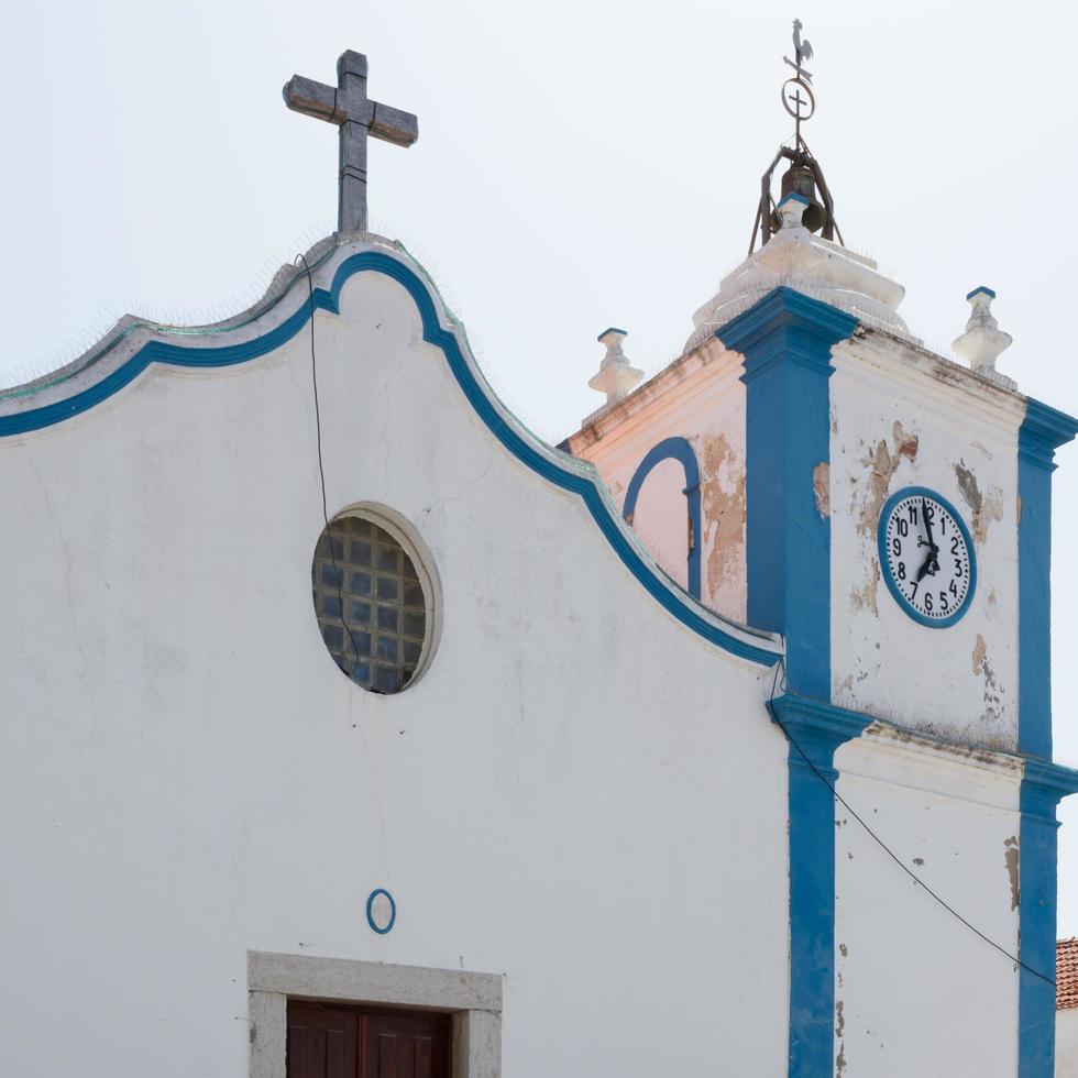 Nahaufnahme einer alten Kirche mit Uhrturm und katholischem Kreuz. Alentejo, Portugal foto