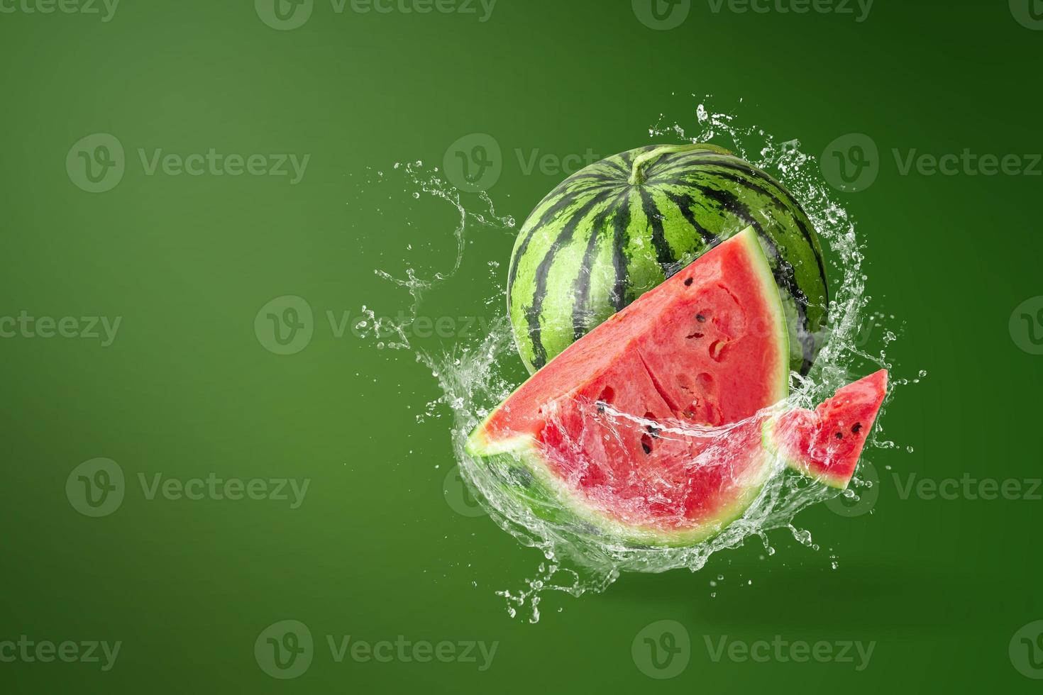 Wasser spritzt auf geschnittene Wassermelone auf grünem Hintergrund foto