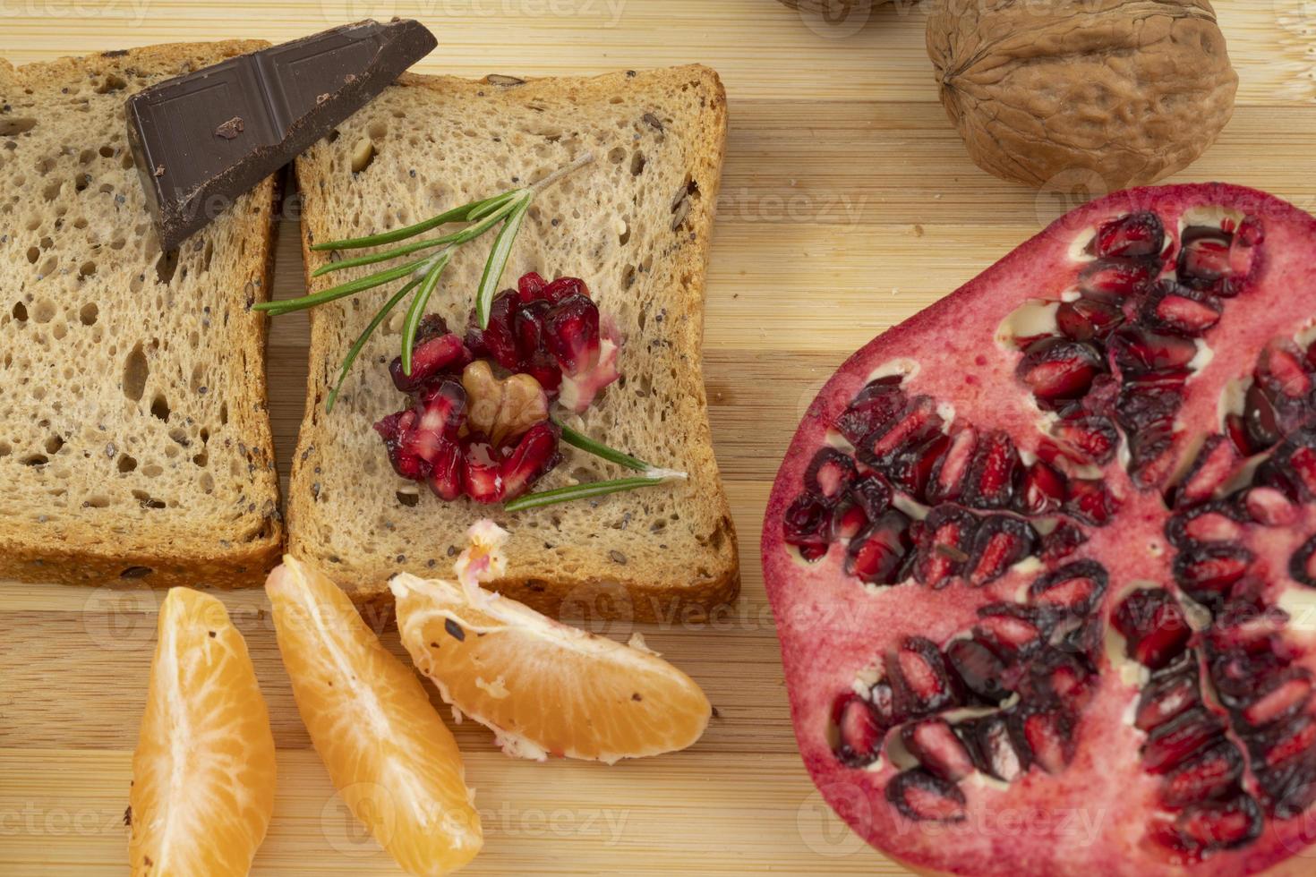 Küchenschneidebrett mit Zwieback, Mandarinen, Granatapfel und Schokolade foto