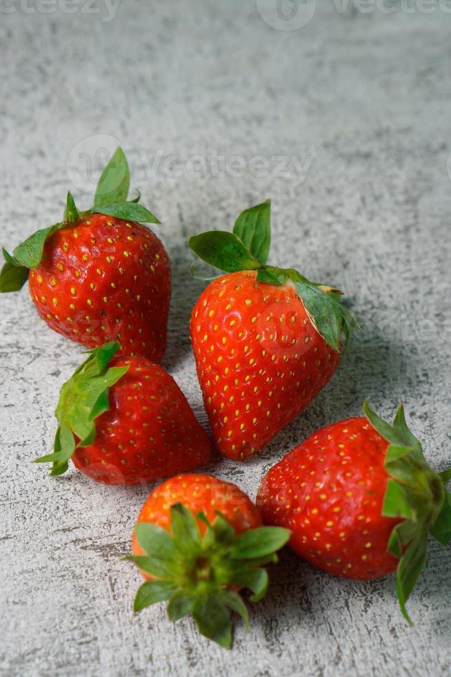 Reife Erdbeeren mit Blättern auf Zementfliesen foto