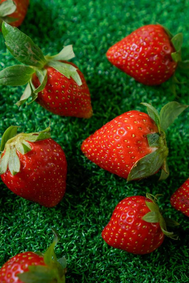 Reife Erdbeere mit Blättern auf grünem Gras foto