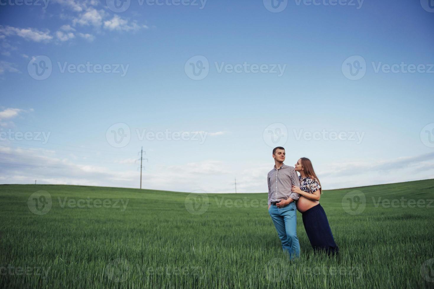 glückliche familie, die in einem feld des grünen weizens umarmt foto