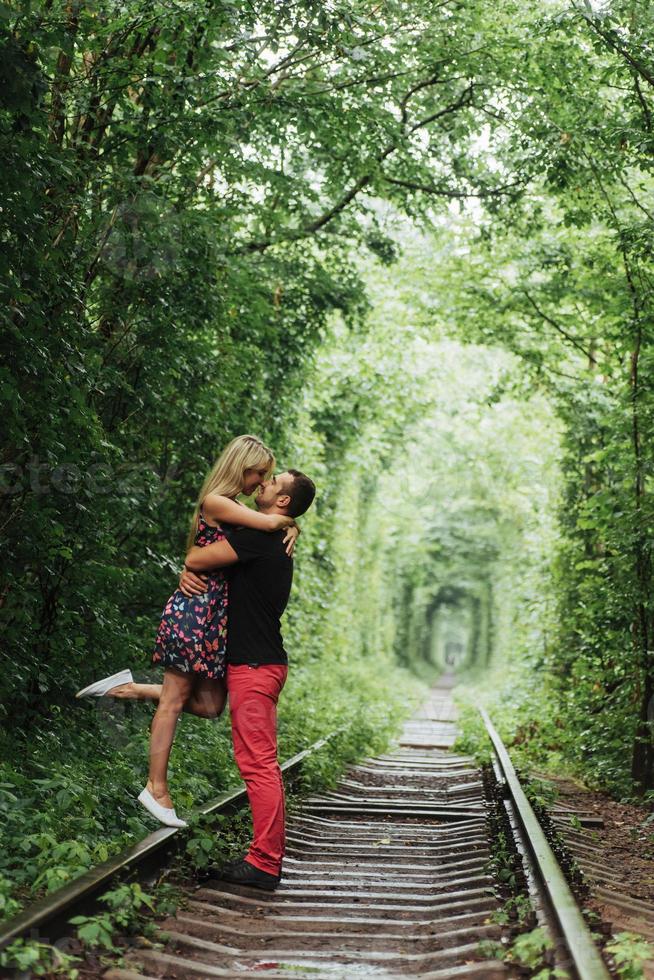 Liebespaar in einem Tunnel aus grünen Bäumen auf der Eisenbahn foto