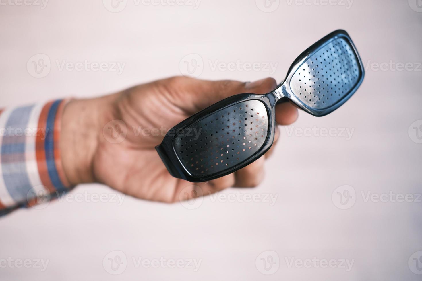 Halten einer Perforationsbrille mit Löchern zum Trainieren des Sehvermögens foto