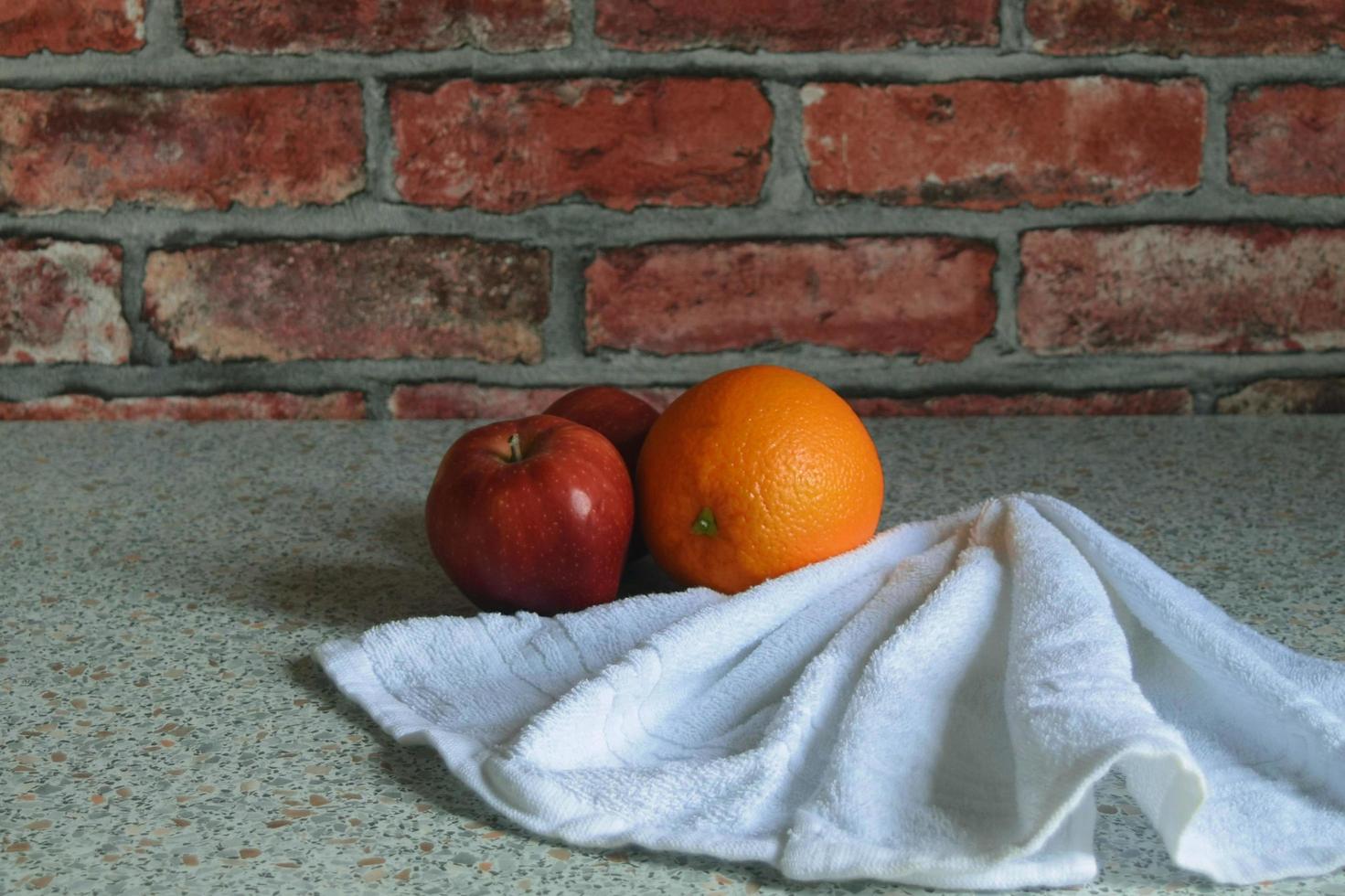 Stillleben mit Äpfeln und Orangen auf dem Hintergrund einer roten Backsteinmauer foto