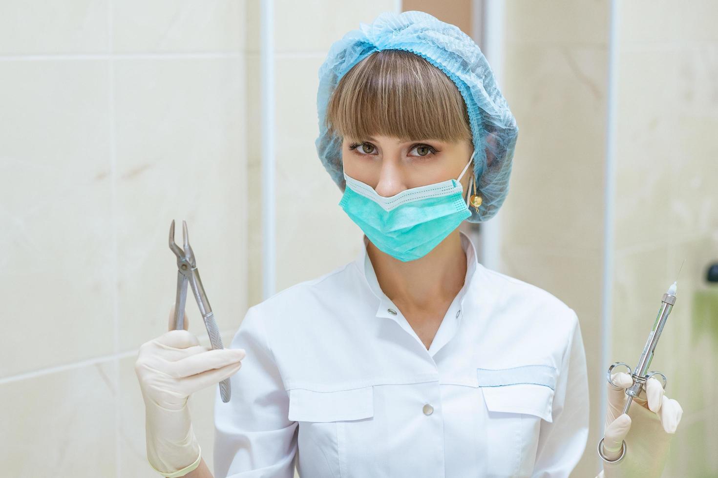 Ärztin in Maske mit Werkzeugen in der Hand foto