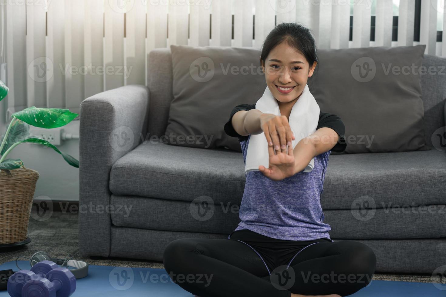 asiatische frau, die sich während eines yoga-kurses mit zu hause ausdehnt. foto