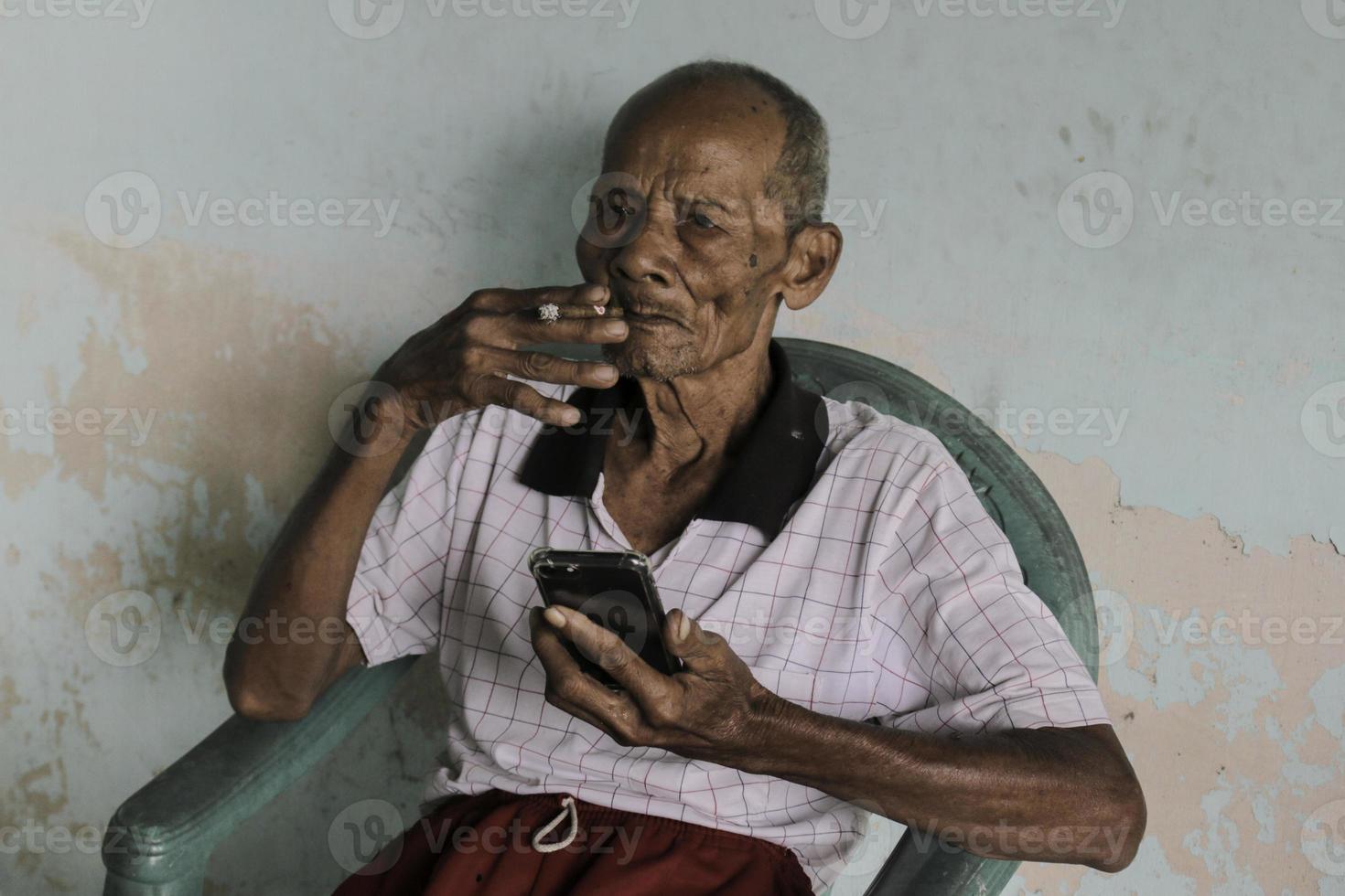 ein porträt des indonesischen alten opas, der das smartphone anruft. foto