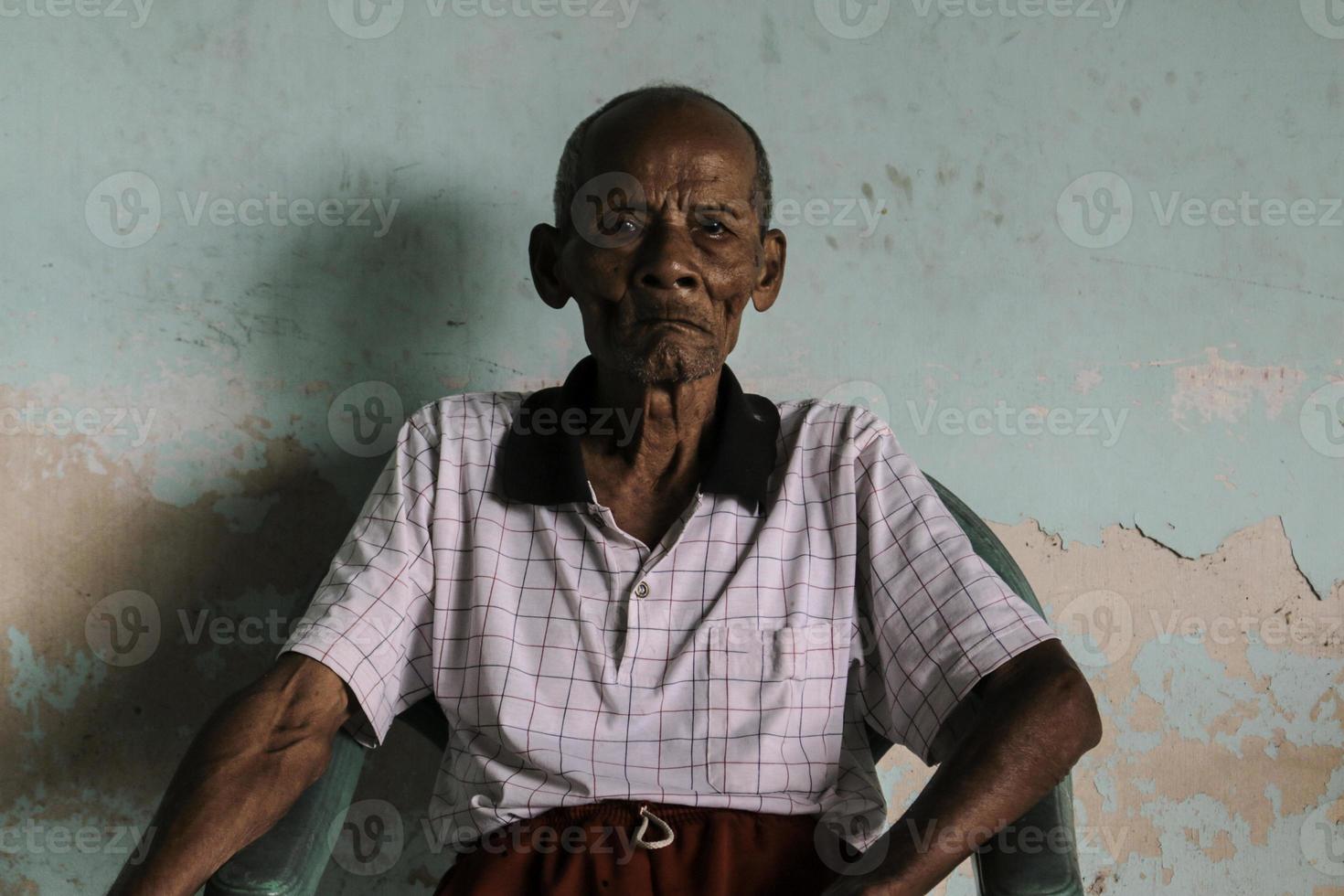 ein porträt des indonesischen alten opas, der auf dem stuhl sitzt foto