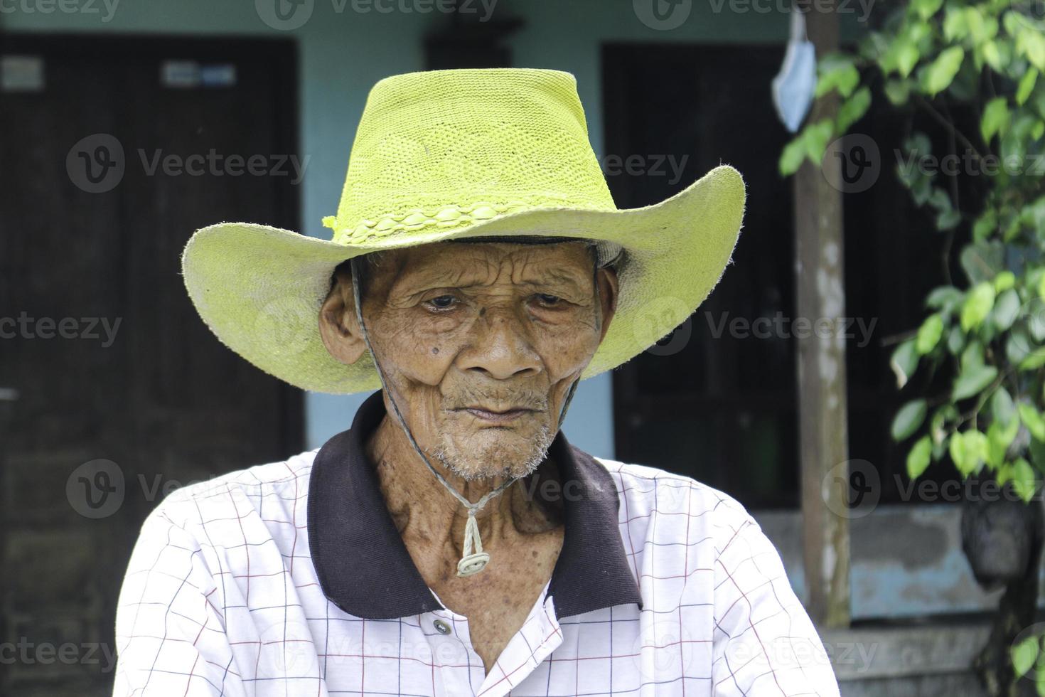 ein porträt eines indonesischen alten bauern trägt einen gelben hut mit einem alten fahrrad foto