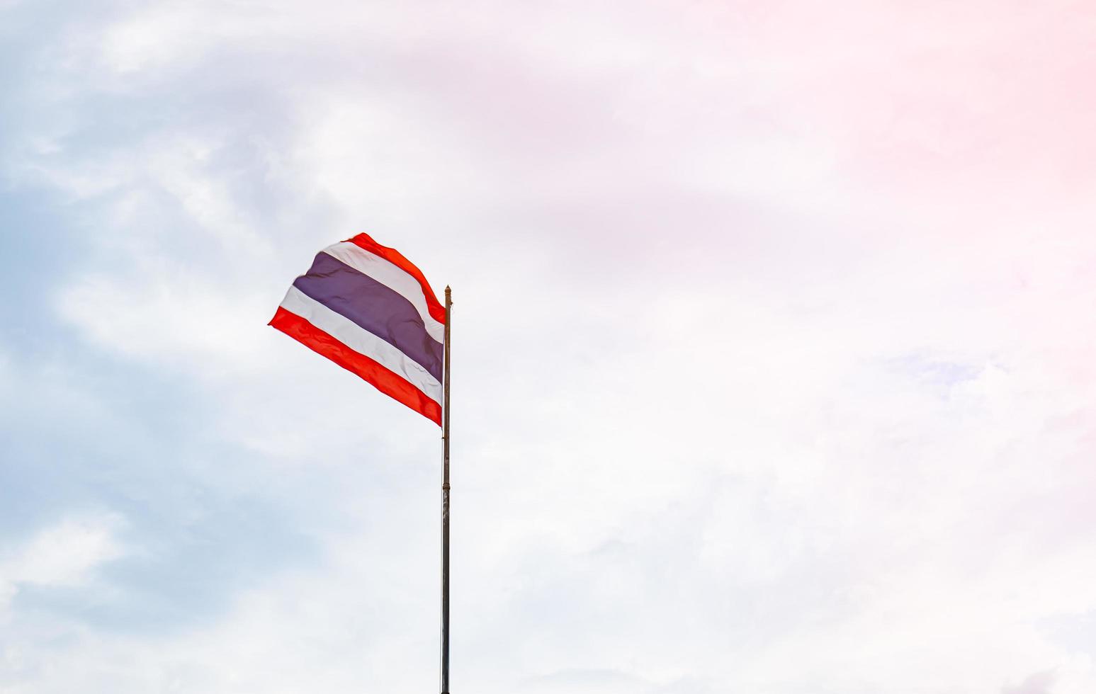 die thailändische flagge wurde vom wind geweht und flatterte an der stange. hol dir die sonne sei stolz auf die thailänder in einem unabhängigen land besteht die flagge aus rot, blau und weiß. foto