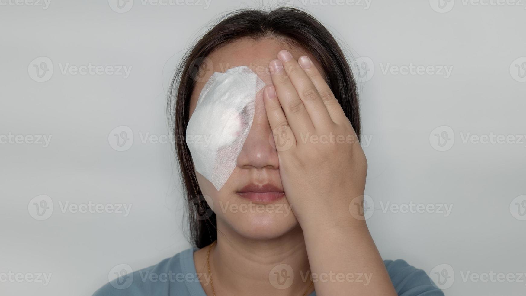 systemisches Auge Frau, die an der Hordeolum-Krankheit behandelt wird, indem sie den Eiter durchsticht und auskratzt, dann mit einem Mulltuch abdeckt und Ihre Augen schnell mit den Händen bedeckt. foto