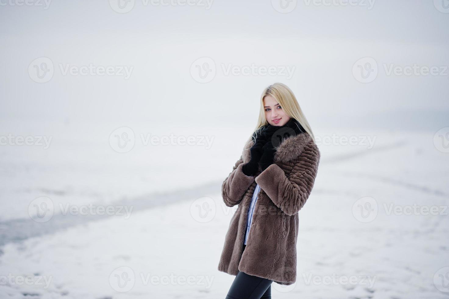 Porträt des blonden Mädchens der jungen Eleganz in einem nebligen Fluss des Pelzmantelhintergrundes auf Wintereis. foto