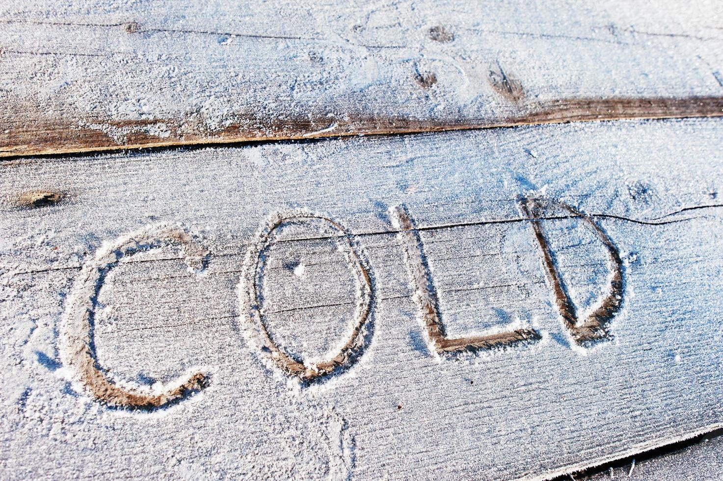 Kälte geschrieben auf einem hölzernen Hintergrund mit Frost foto