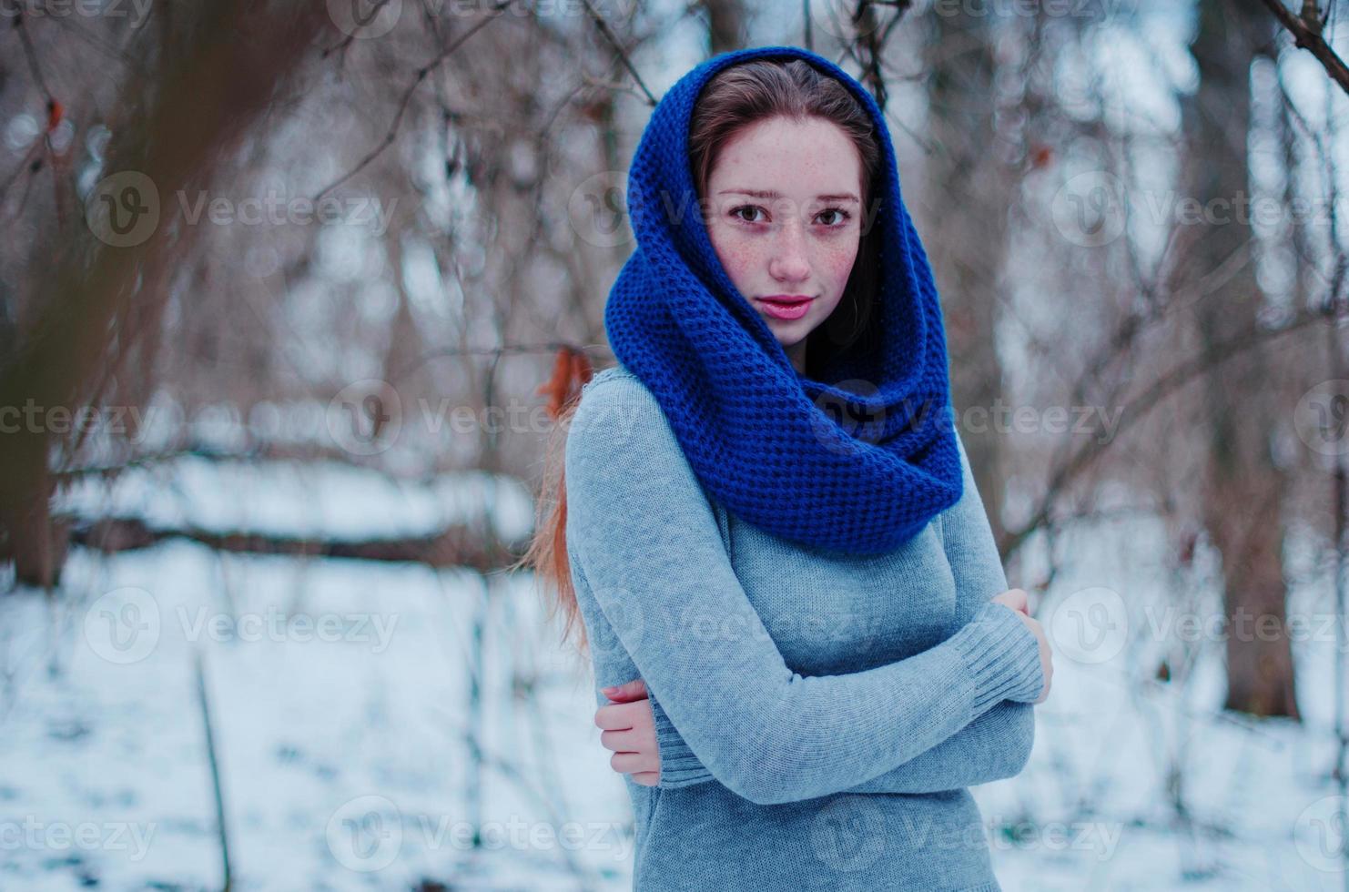 Porträt eines jungen Mädchens mit roten Haaren und Sommersprossen, das am Wintertag einen blau gestrickten Wollschal trägt. foto