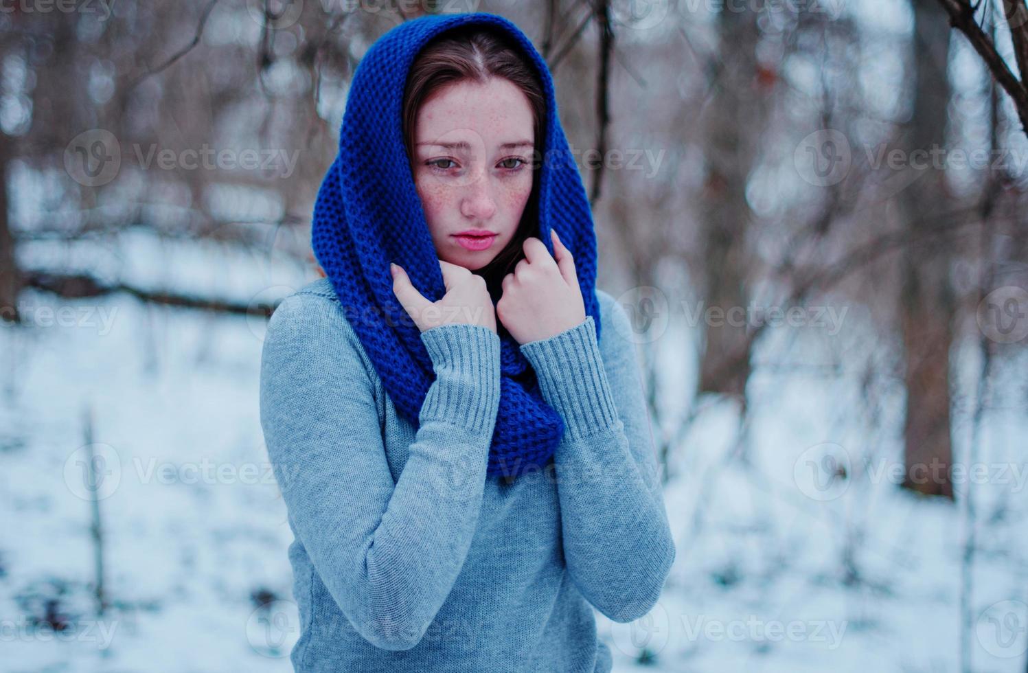 Porträt eines jungen Mädchens mit roten Haaren und Sommersprossen, das am Wintertag einen blau gestrickten Wollschal trägt. foto