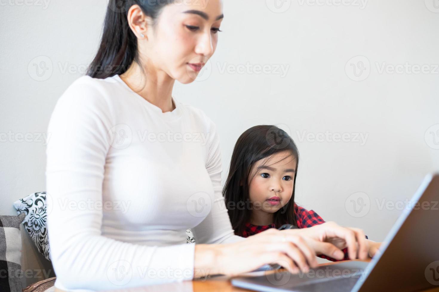 asiatische mütter bringen ihren töchtern während der schulferien zu hause bei, ein buch zu lesen und notizbücher und technologie für das online-lernen zu verwenden. pädagogische Konzepte und Aktivitäten der Familie foto