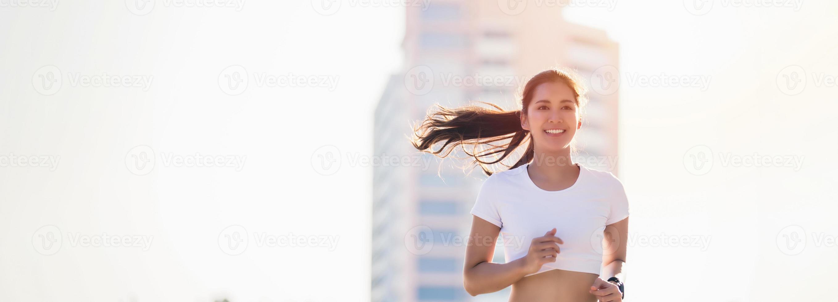 lächelnde asiatische junge Fitnesssportlerin, die in einem städtischen Gebiet läuft und sportliche Menschen trainiert, gesunde Lebensweise und Sportkonzepte foto