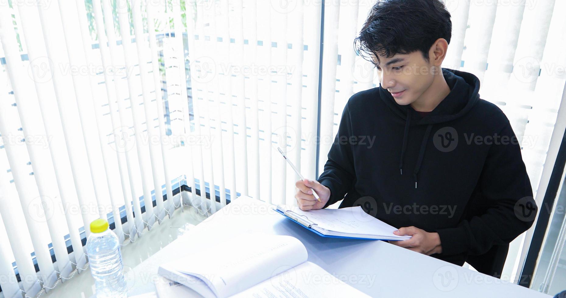 asiatische männliche studenten lächeln und lesen ein buch und verwenden ein notizbuch, um ideen in der arbeit und im projekt auszutauschen. und überprüfen Sie das Buch auch vor der Prüfung foto
