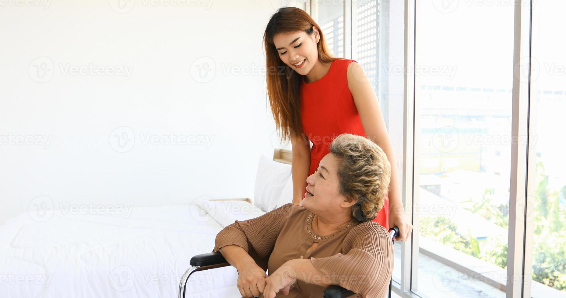 fröhliche frau, die sich um ihre großmutter im rollstuhl kümmert foto