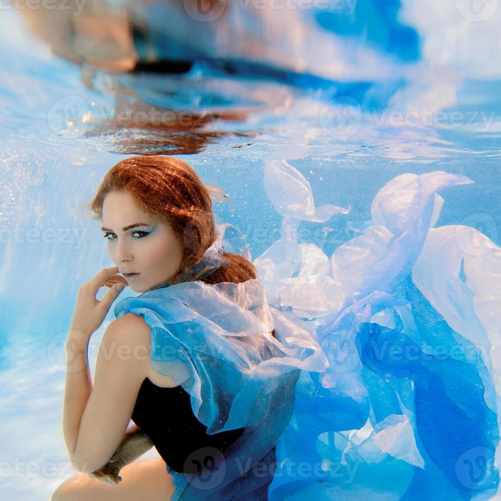 Unterwassermodeporträt der schönen jungen Frau im blauen Kleid foto