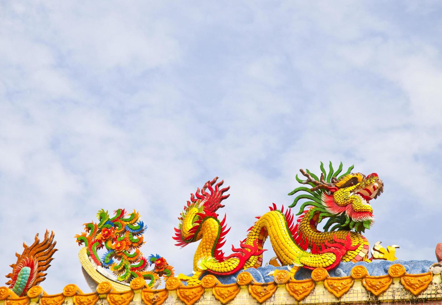 Goldene künstlerische große gelbe asiatische Drachenstatue auf dem Dach eines Tempels foto
