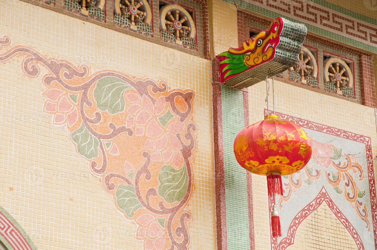 Traditionelle einfache Drachenmalereistatue mit roter chinesischer Laterne, die im asiatischen Tempel hängt foto