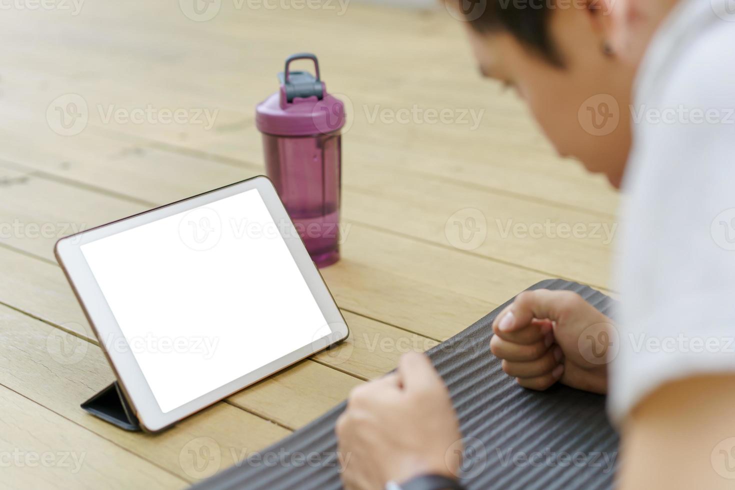Mockup leerer Bildschirm des Tablets. Mann, der eine Plankenübung macht und auf Tablet schaut. foto
