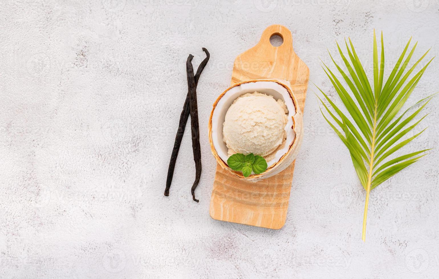 Kokoseis-Aromen in der Hälfte des Kokos-Setups auf weißem Steinhintergrund. Sommer und süßes Menükonzept. foto