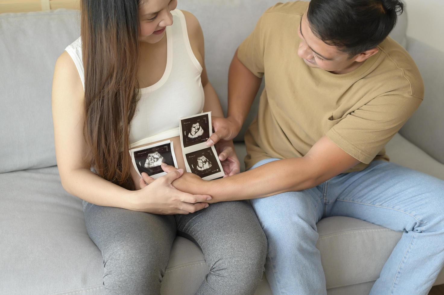 junge schwangere frau mit ehemann, der ultraschallfoto des neugeborenen, mutterschafts- und familienkonzeptes hält foto